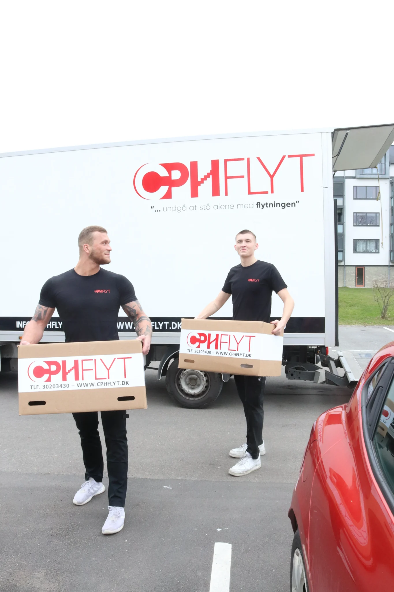To flyttemænd fra CPHFLYT med flyttekasser foran flyttevogn