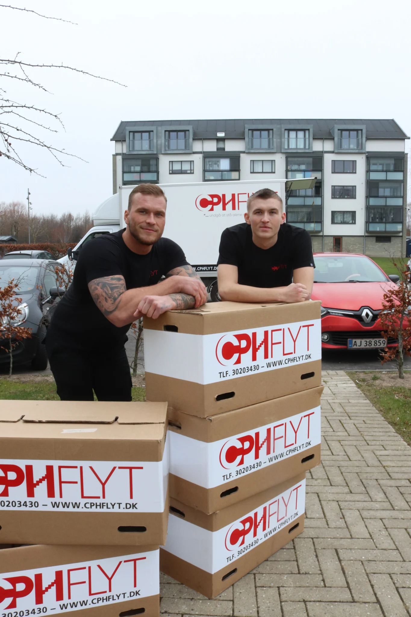 To flyttemænd fra CPHFLYT ved flyttekasser foran flyttebil